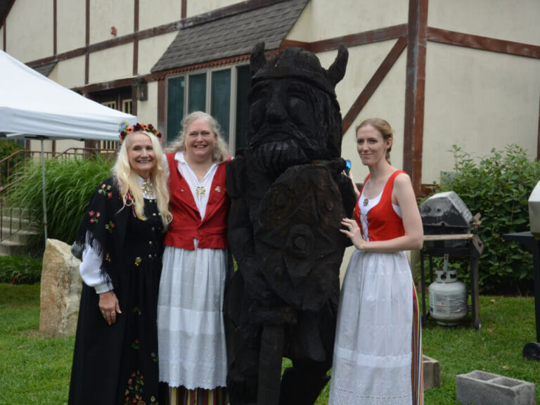 women posing with a viking statue